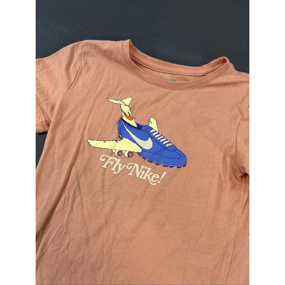 Nike "Fly Nike!" graphic tee in a light orange-red color